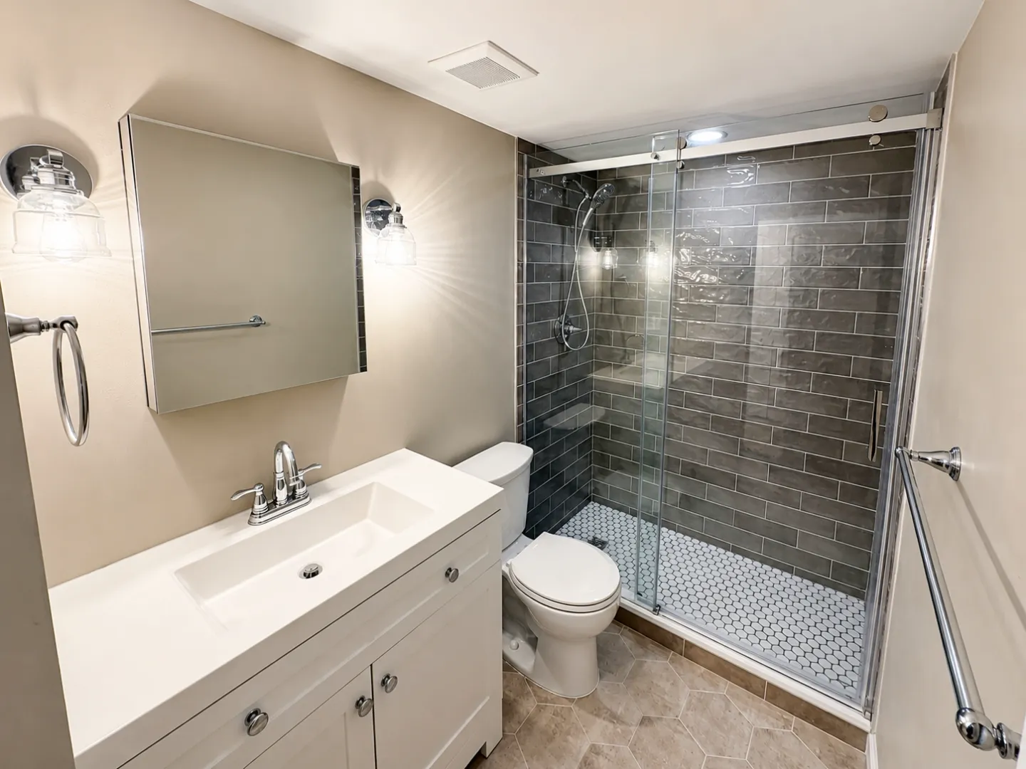 Basement bathroom with glass shower, dark subway tile, and chrome fixtures